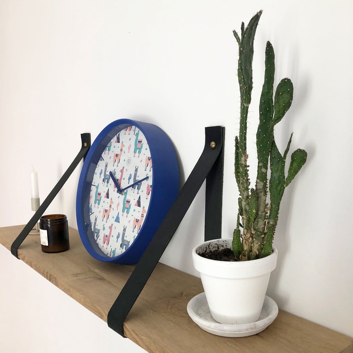 Een ronde wandklok met een blauwe rand en een witte wijzerplaat versierd met kleurrijke alpaca’s, cactussen en bergen. Perfect voor kinderkamer of speelruimte met een vrolijke, decoratieve stijl.