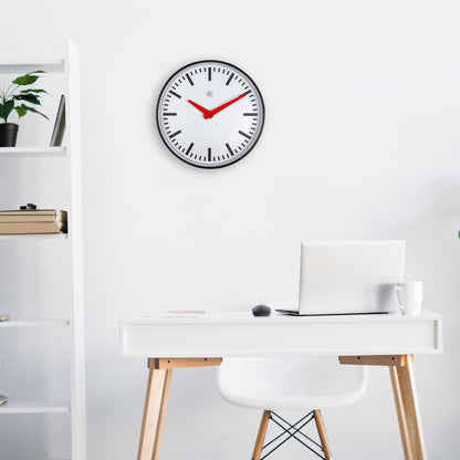 Een minimalistische wandklok met witte wijzerplaat, zwarte indexen en opvallende rode wijzers. Zilveren rand en zwart frame voor een moderne, functionele uitstraling in woon- of kantoorruimte.