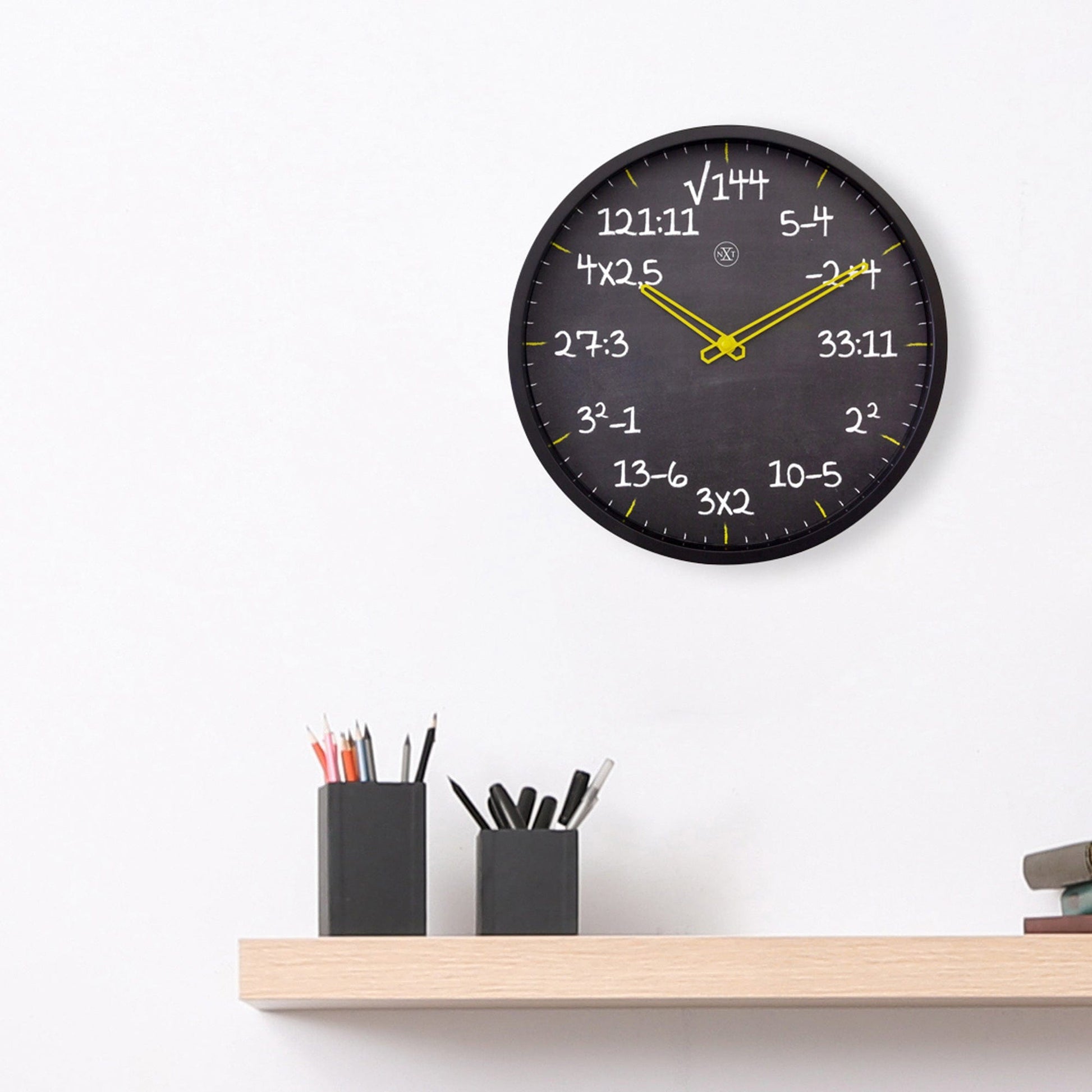 Een zwarte wandklok met gele wijzers en witte wiskundige formules als tijdsaanduidingen, ideaal voor een wiskundelokaal of studieomgeving.
