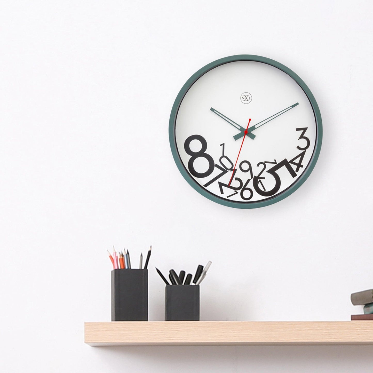 Een moderne wandklok met een groene rand en een witte wijzerplaat, waarop zwarte, gestileerde cijfers en een rode secondewijzer duidelijk zichtbaar zijn. Ideaal voor een minimalistische kamer of als decoratief element in een woonkamer.