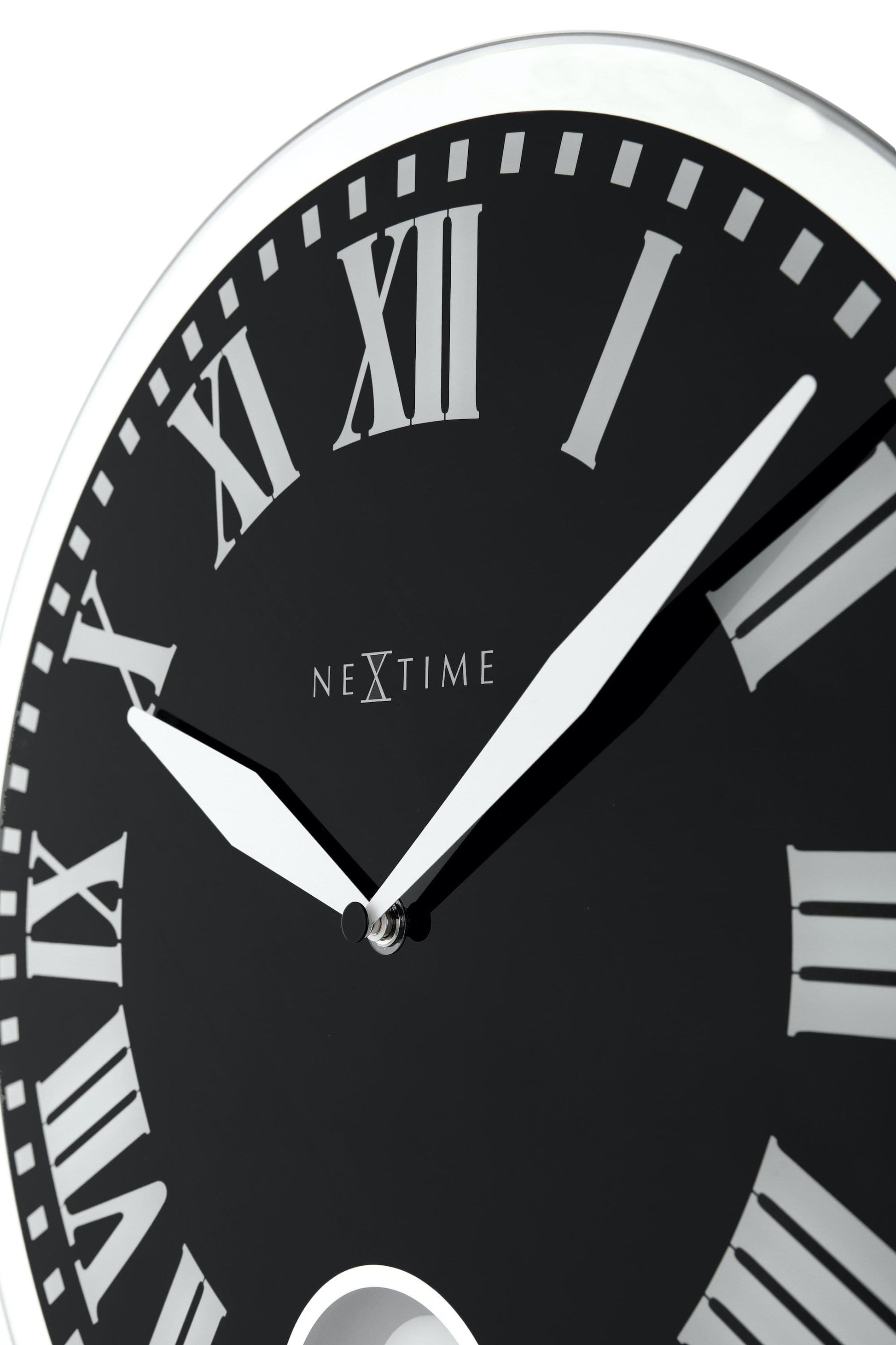 Een elegante wandklok met zwart wijzerplaat en zilveren Romeinse cijfers, voorzien van een witte pendel en het merk NEXtime. Perfect voor moderne interieurs en als decoratief element in woon- of kantoorruimtes.