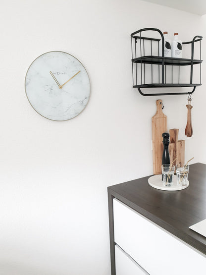 Een elegante wandklok met wit marmeren oppervlak en goudkleurige wijzers. De ronde klok heeft een goudkleurige rand en het merk 'NEXTIME' in het midden, ideaal voor moderne interieurs.