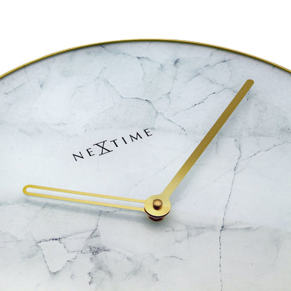 Een elegante wandklok met wit marmeren oppervlak en gouden wijzers en kader. Het merk 'NEXTIME' is zichtbaar in het midden, ideaal voor moderne interieurs en als decoratief element in woon- of kantoorruimtes.