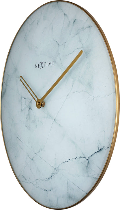 Een elegante wandklok met wit marmeren oppervlak en goudkleurige wijzers en rand. Het merk 'NEXTIME' is zichtbaar in het midden, geschikt voor moderne interieurs en als decoratief element in woon- of kantoorruimtes.