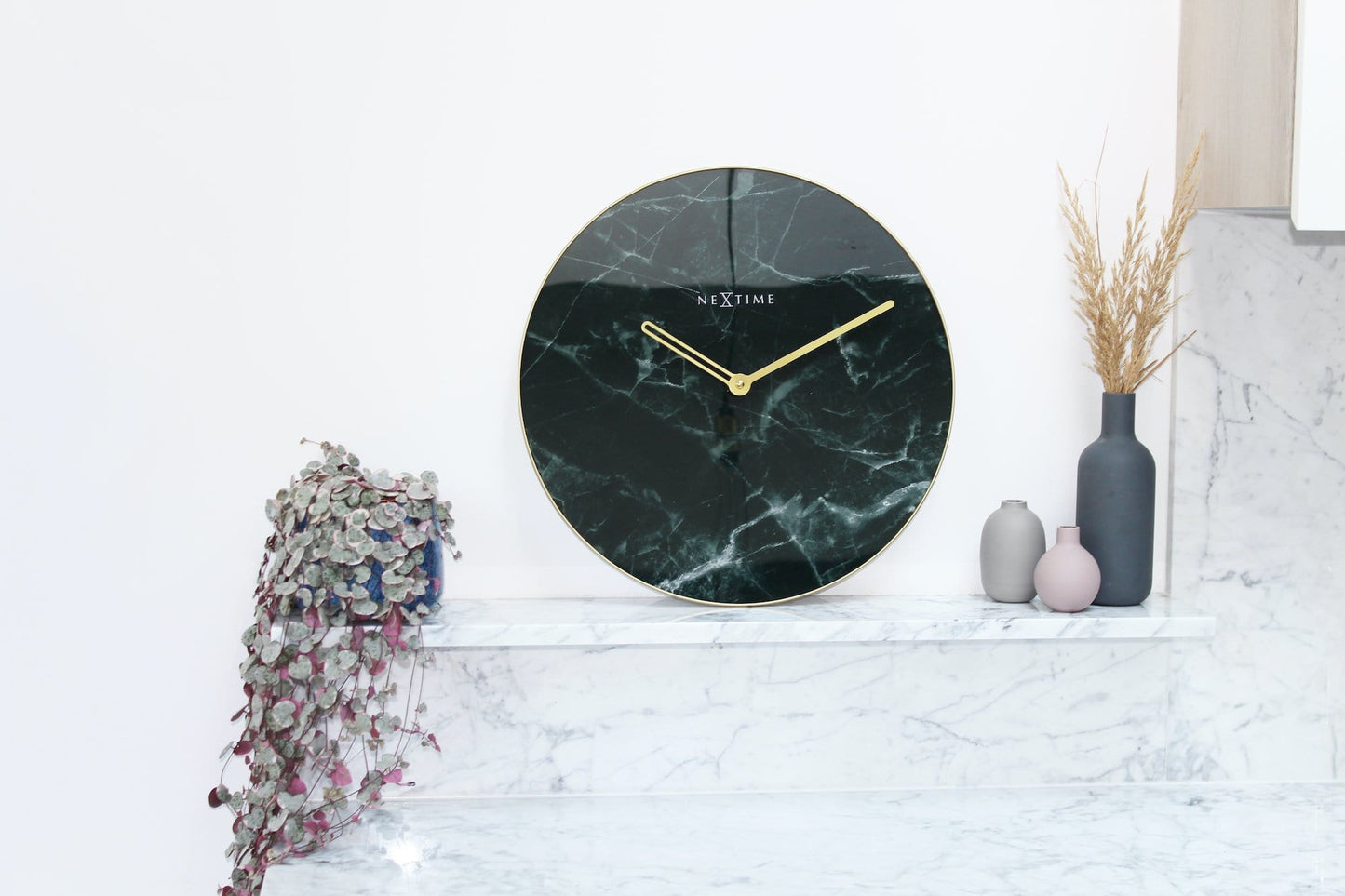Een elegante wandklok met donker marmeren oppervlak en goudkleurige wijzers. De minimalistische klok is ideaal voor moderne interieurs en past perfect in een woonkamer of slaapkamer.