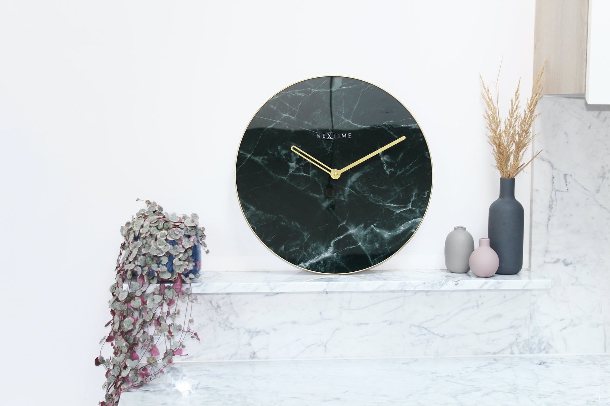 Een elegante wandklok met donker marmeren oppervlak en goudkleurige wijzers. De minimalistische klok is ideaal voor moderne interieurs en past perfect in een woonkamer of slaapkamer.