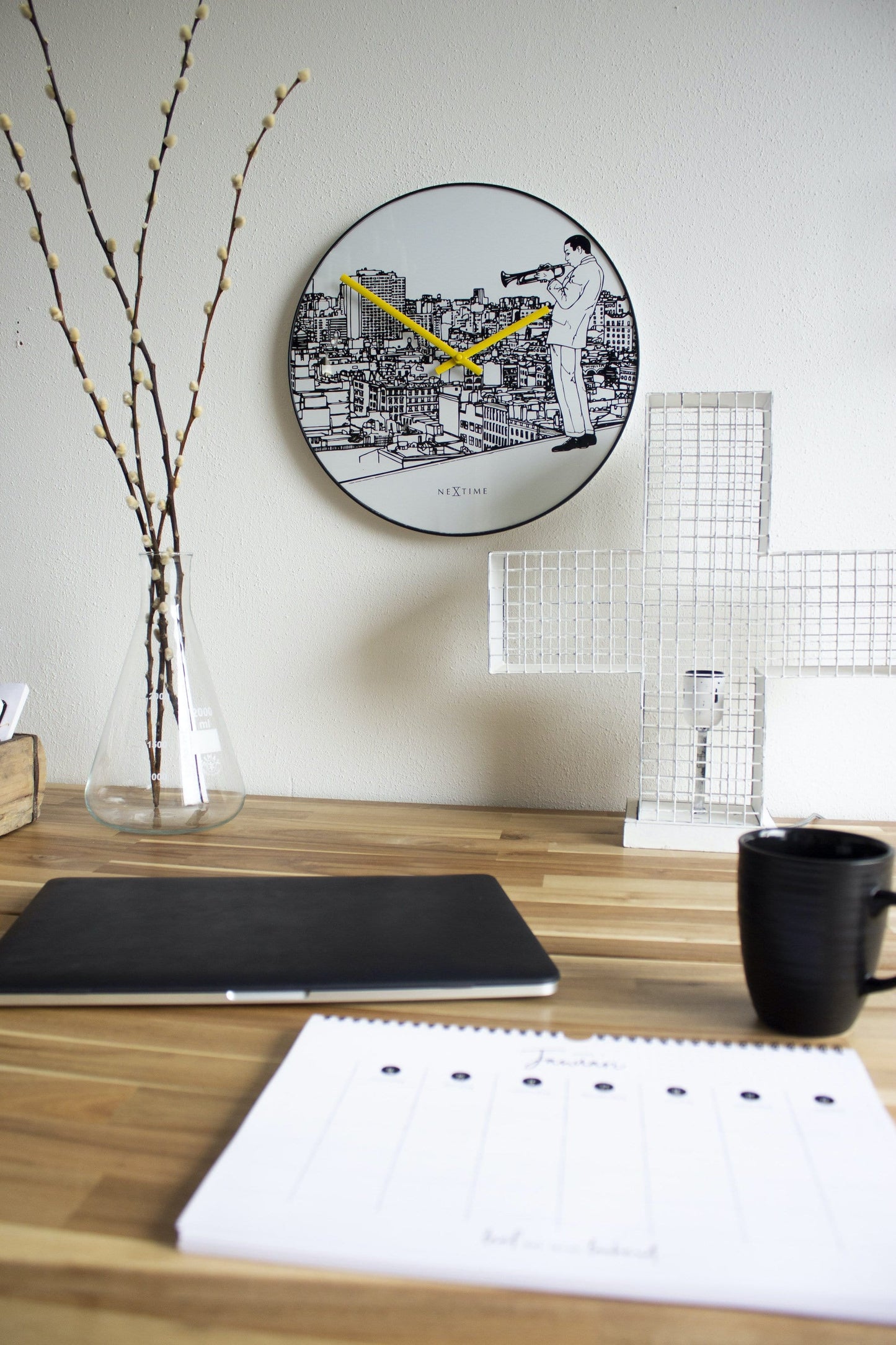 Een ronde wandklok met zwart-wit stadsillustratie en een muzikant met trompet. Geel wijzerplaat en zwarte kader, ideaal voor een moderne woonkamer of kantoordecoratie.