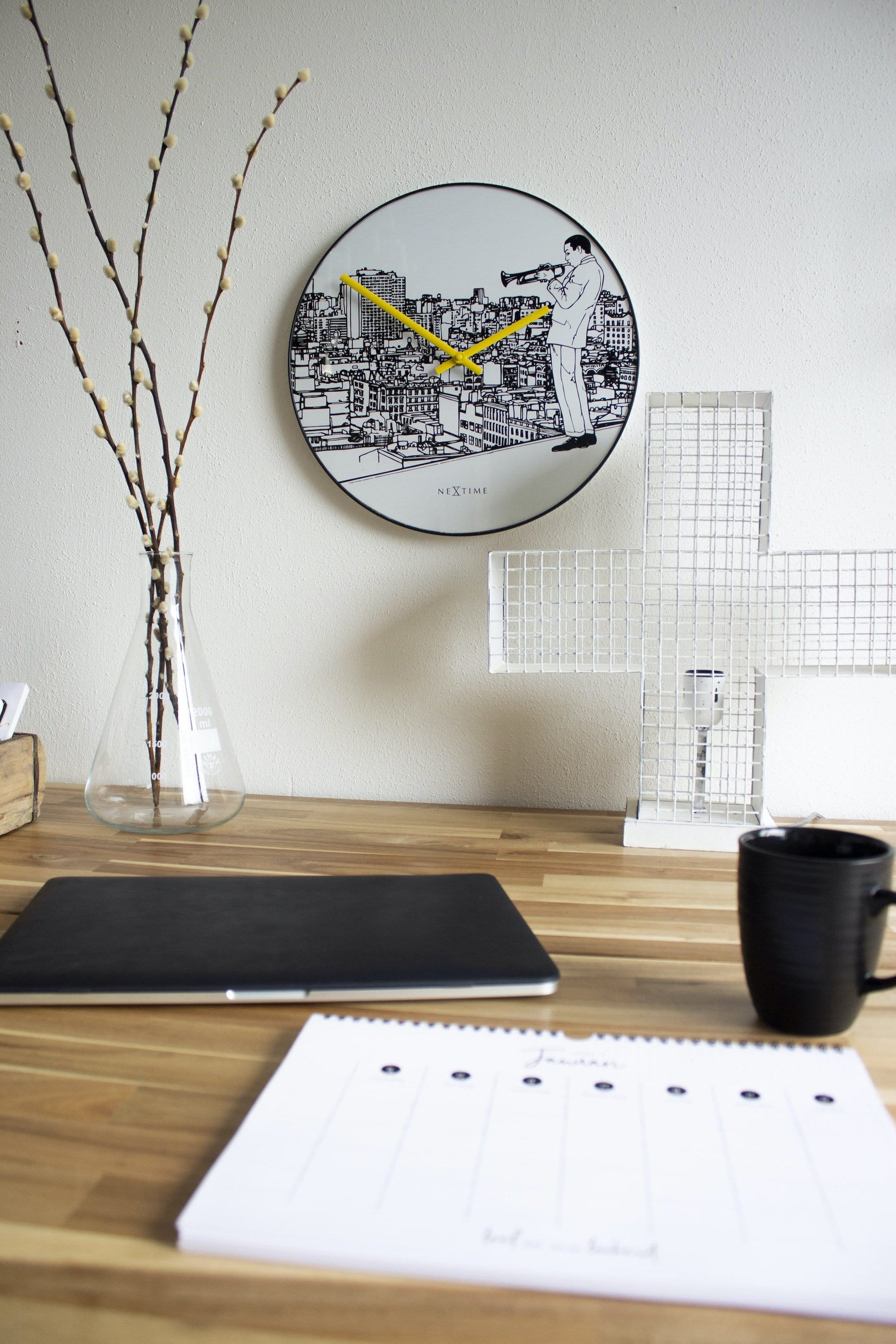 Een ronde wandklok met zwart-wit stadsillustratie en een muzikant met trompet. Geel wijzerplaat en zwarte kader, ideaal voor een moderne woonkamer of kantoordecoratie.