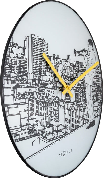 Een ronde wandklok met zwart-wit stadsillustratie en een man met trompet. Geel wijzerplaat en 'NEXTIME' logo. Perfect voor woonkamer of kantoordecoratie.