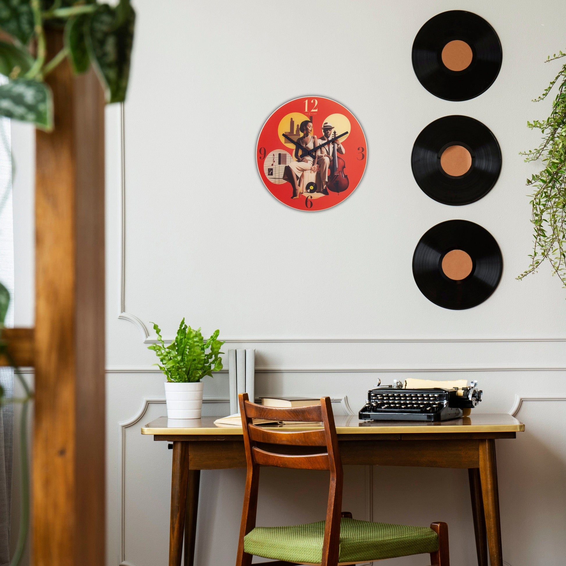 Rode wandklok met retro jazzillustratie van een vrouw en man met cello, goudkleurige cijfers en vinyldetails. Perfect voor jazz- of muziekliefhebbers die een stijlvolle decoratie zoeken.