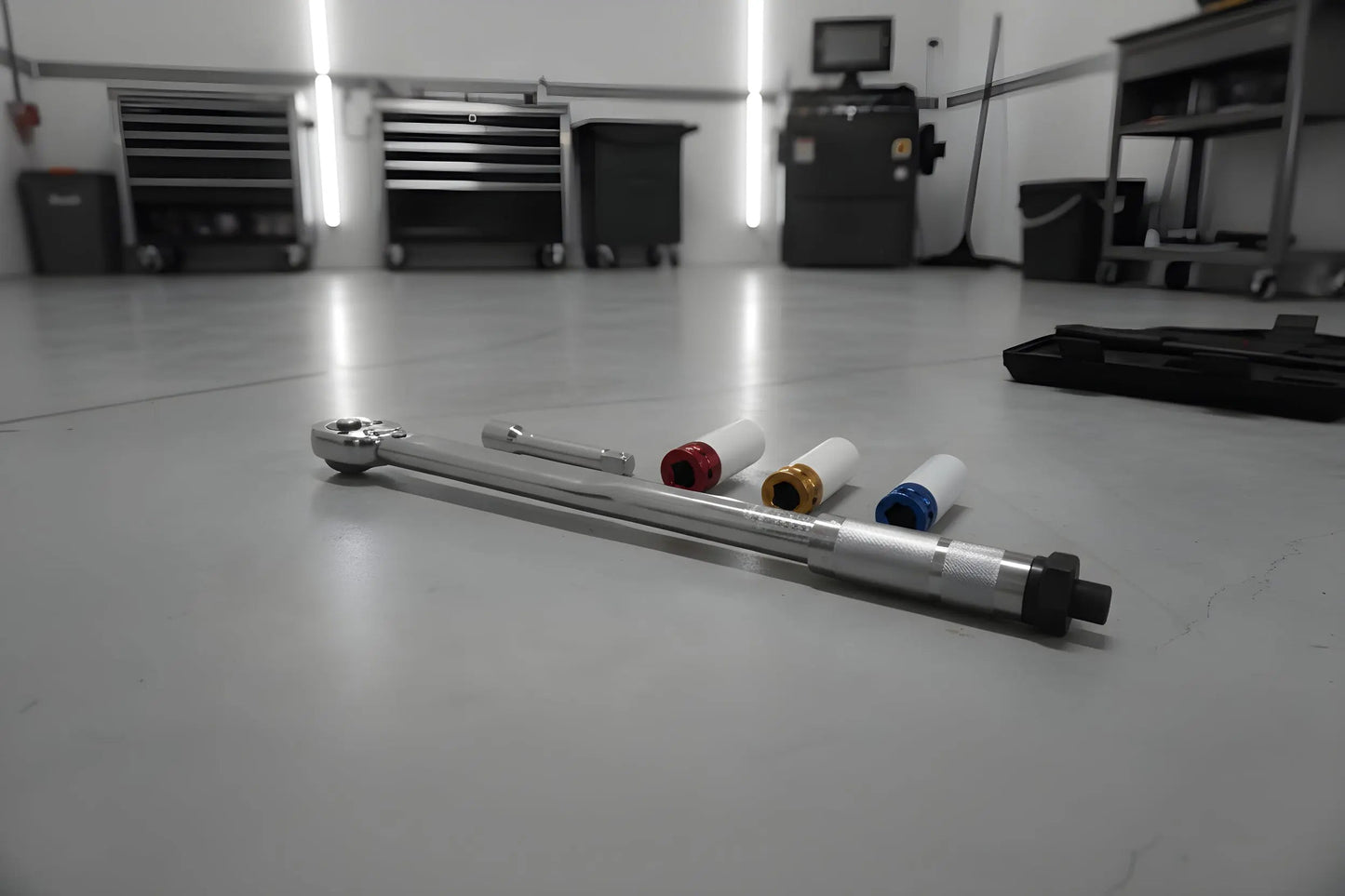 Zilverkleurige schroefspanner in zwarte houder, met kleurrijke (blauw, geel, rood) aanpasbare koppen. Geschikt voor precisiewerkzaamheden in de automotieve en reparatiewereld.