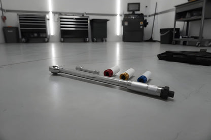 Zilverkleurige schroefspanner in zwarte houder, met kleurrijke (blauw, geel, rood) aanpasbare koppen. Geschikt voor precisiewerkzaamheden in de automotieve en reparatiewereld.