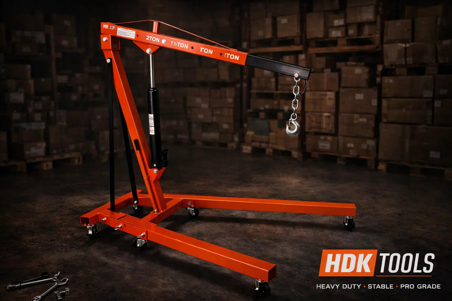 Een oranje, staafvormige kraan met wielen, voorzien van een zichtbare belastingindicatie van 2 ton, staat klaar in een magazijn. Het is een professionele, zwaarbelaste kraan geschikt voor industriële opslagruimtes.