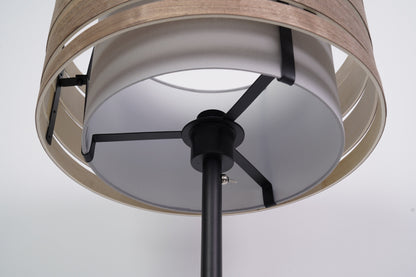Een moderne, zwarte vloerlamp met een gestreepte, witte kap en een dunne steel, ideaal voor minimalistische interieurs. Perfect voor woonkamer- of slaapkamerverlichting.