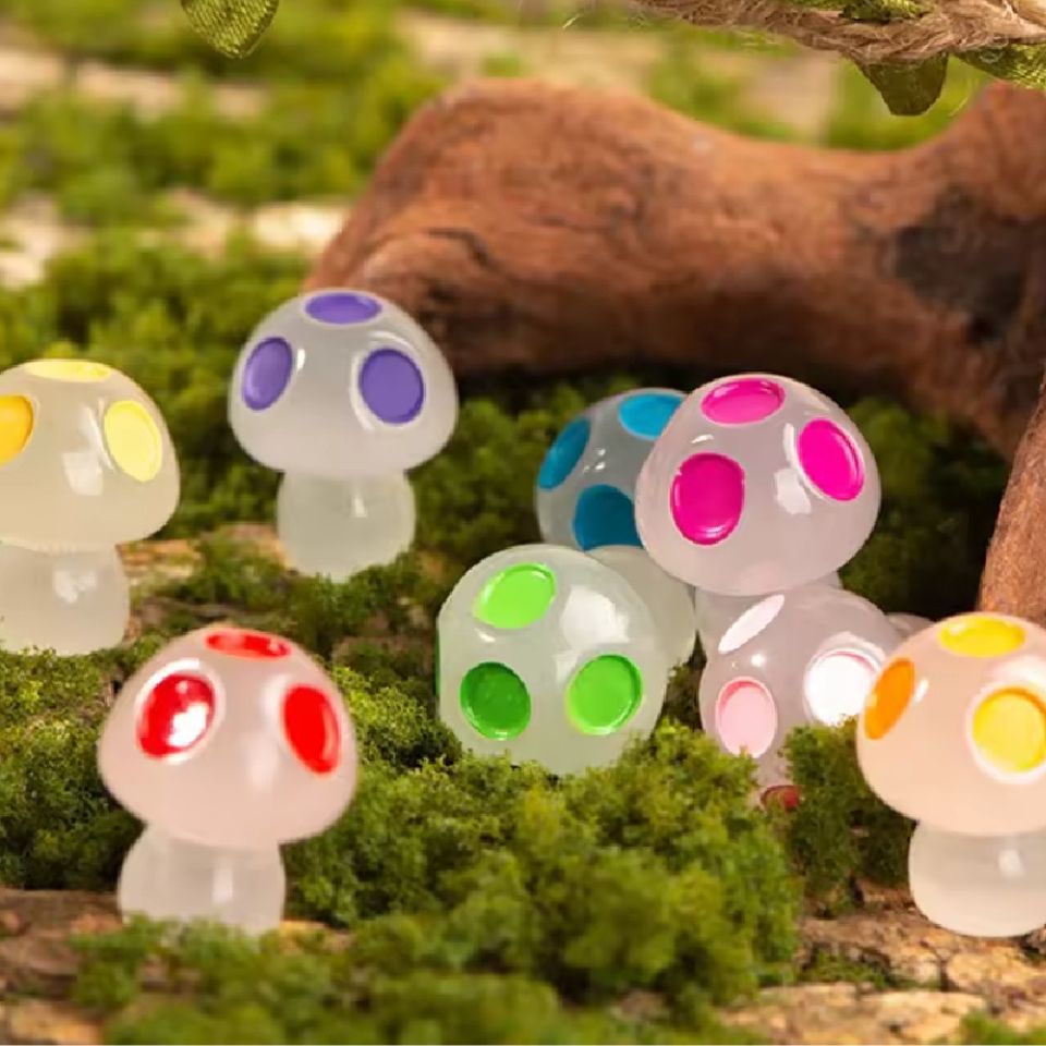 Kleurrijke glazen paddenstoelen met heldere stippen staan op groen mos, perfect voor een magisch tuininterieur. Ideaal als decoratie voor een kinderkamer of als sfeerverlichting in een buitenruimte.