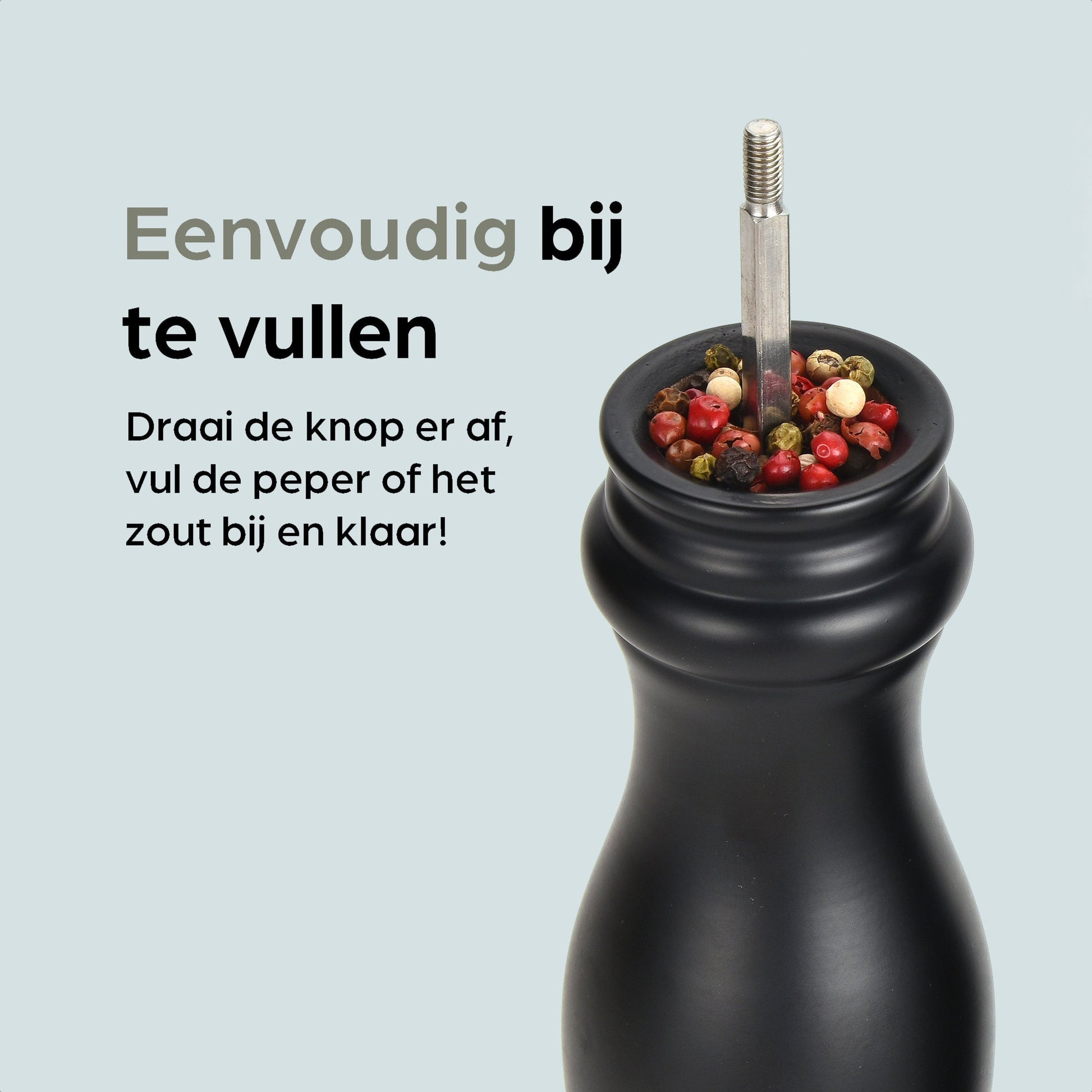Zwarte houten pepermolen en zoutmolen met goudkleurige doppen, geplaatst op een zwarte standaard met het merk 'hermanos'. Inclusief vier vervangende doppen voor keukengebruik.
