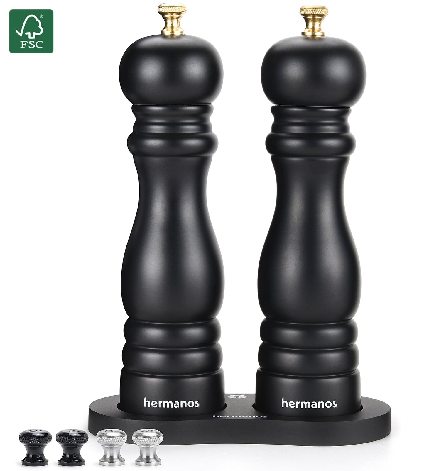Zwarte houten pepermolen en zoutmolen met goudkleurige doppen, geplaatst op een zwarte standaard met het merk 'hermanos'. Inclusief vier vervangende doppen voor keukengebruik.