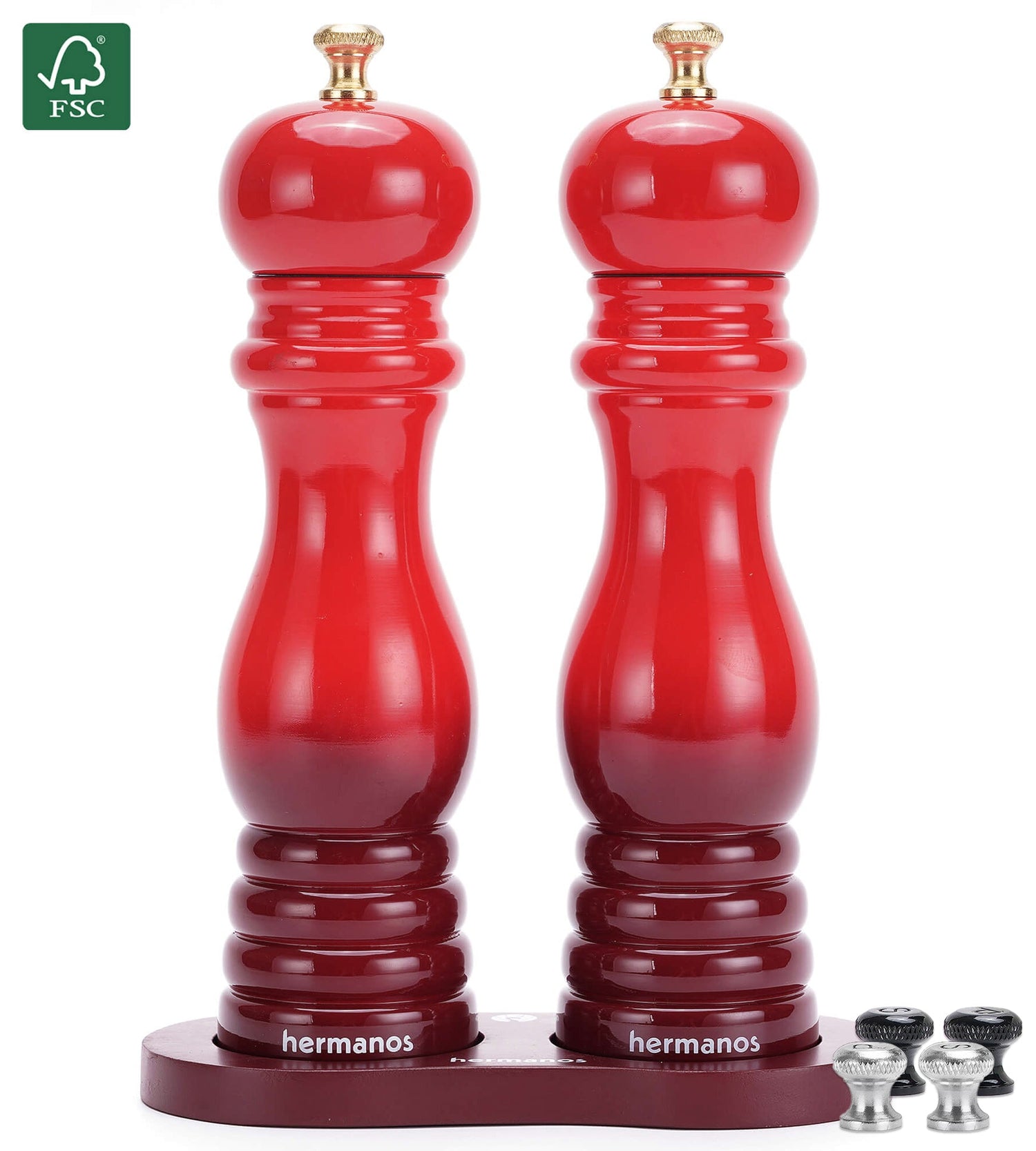 Rode houten peper- en zoutmolen van Hermanos, met glanzende lak en goudkleurige doppen, geplaatst op een donkerrode standaard met extra doppen voor keukengereedschap. Ideaal voor moderne keukens en gourmet kookplekken.
