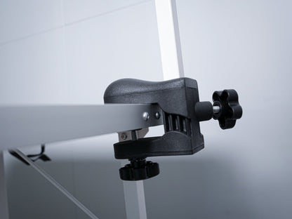 Een witte, opvouwbare hondensnijtafel met zwarte oppervlakte en twee hangende riemen, geschikt voor professionele hondensnijden en -verzorging in huis of studio.