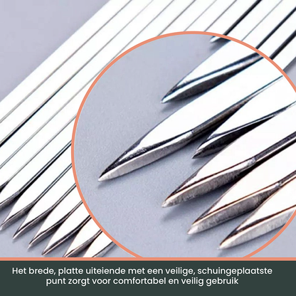 Zilverkleurige, glanzende grillspiesjes met een gegrilde kip- en groentekebab, naast een compacte, metalen houder voor barbecue- en grilltoepassingen.