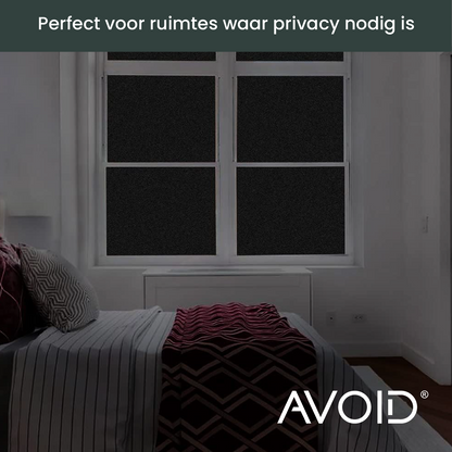 Zwart, mat glasfolie op een wit raamkozijn, zacht afgebeeld tegen een groene, onscherpe achtergrond. Ideaal voor privacy en zonbescherming in woon- en kantoorruimtes.