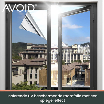 Donkergrijze, matte zonwering op een wit raamkozijn, met een zachte groene tuinachtergrond. Ideaal voor privacy en zonbescherming in woon- en kantoorruimtes.
