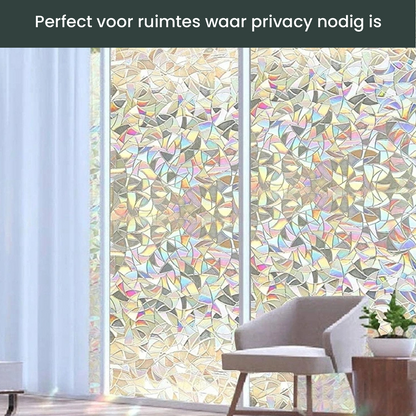 Een zilverkleurige, glinsterende glasfolie met abstracte, veelhoekige patronen bedekt een venster. Deze privacyfolie biedt zichtbescherming en zorgt voor een stijlvolle, lichtdoorlatende decoratie.
