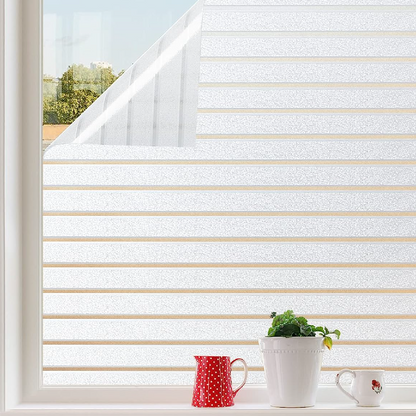 Wit horizontale glasfolie met mat afwerking op een raam, zacht gefilterd zonlicht en groene bomen op de achtergrond. Ideaal voor privacy en lichtregulatie in woon- en kantoorruimtes.