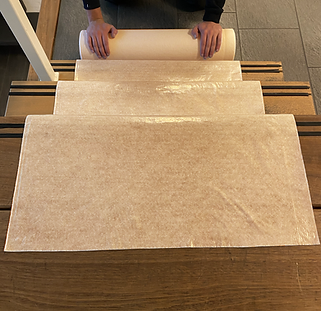 Een rol beige Perfect Cover beschermfolie, met duidelijke merklabel en gebruiksaanwijzingen, geschikt voor tijdelijke bescherming van meubels en vloeren tijdens renovaties of feesten.