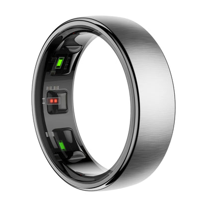 Een zilverkleurige slimme ring met glanzende, getextureerde oppervlakken en zichtbare LED-indicatoren, naast een goudkleurige versie op een draadloze oplader voor gezondheidsmonitoren. - Foto 9