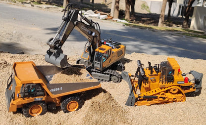 Grote, realistische RC-graafmachine in zwart en geel, met zichtbare trekkettingen en een schep die zand opvangt. Inclusief afbeeldingen van accessoire