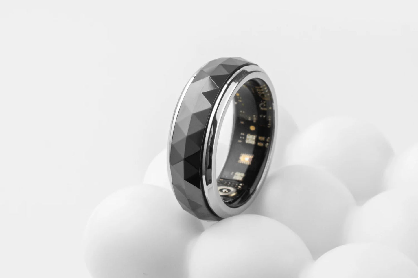 Een COLMi slimme ring met glanzend zilveren rand en facettenstructuur, voorzien van een actieve sensor en groene LED-indicator, geschikt voor dagelijks gebruik en technologische toepassingen. - Foto 30