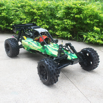 Groene camouflage RC buggy met zwarte banden en metalen frame, klaar voor terreinrijden. Zichtbare motor en stuurwiel op beton, perfect voor buitenple