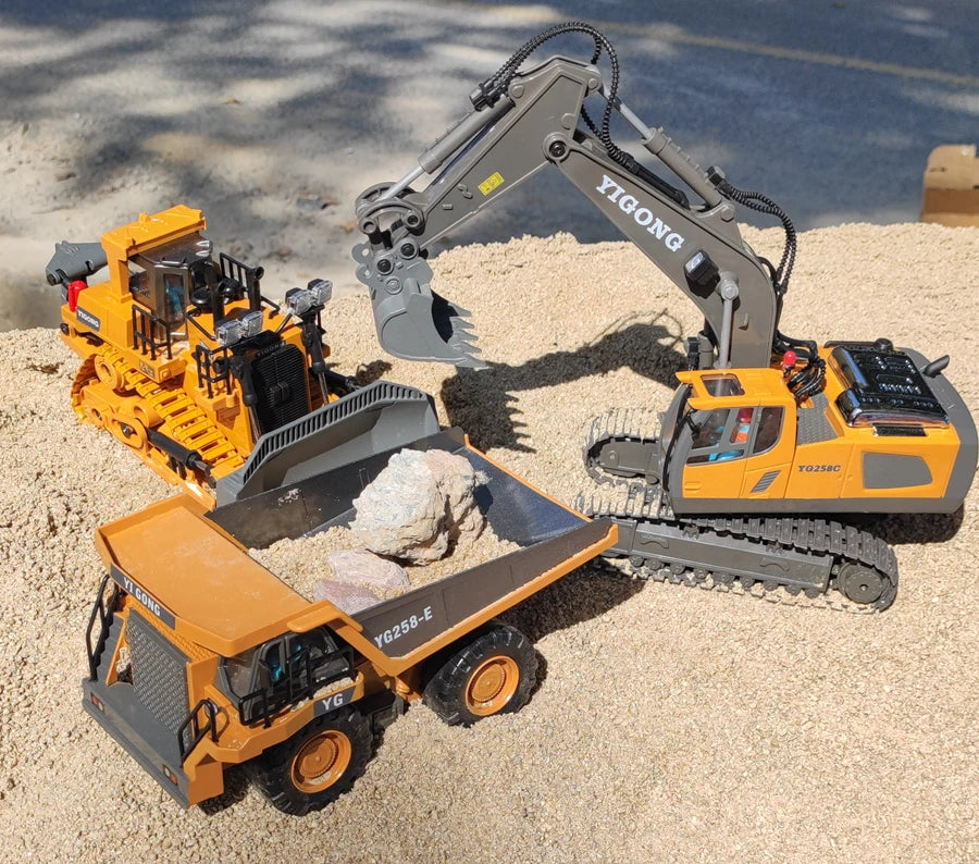 Grote, realistische RC-graafmachine in zwart en geel, met zichtbare trekkerbanden en een schep die zand opvangt. Inclusief afbeeldingen van de verpakk