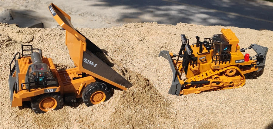 Grote, realistische RC-graafmachine in zwart en geel, met zichtbare trekkerbanden en schep die zand opvangt. Inclusief afbeeldingen van accessoires en