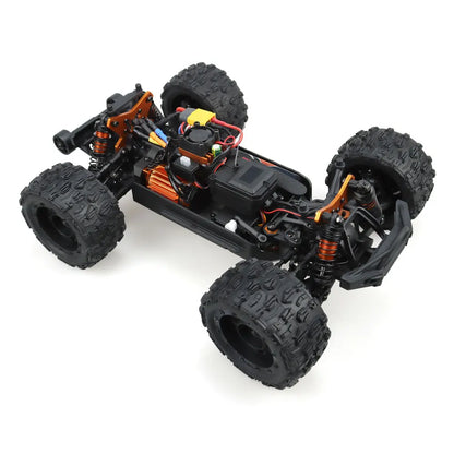 Oranje en blauwe RC monstertruck met zwarte rubberen banden en zichtbare "MT-16" sticker, geplaatst naast zijn zwarte stuurunit voor speelplezier op z