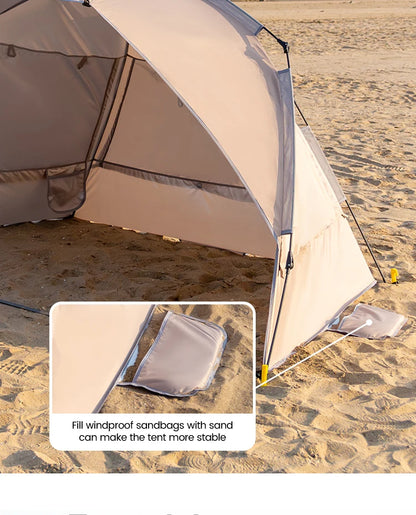 Zilveren vinyl zonnescherm met UPF60+ bescherming, geplaatst op het strand met twee vouwstoelen en tafel. Ideaal voor zonbescherming tijdens kamperen 