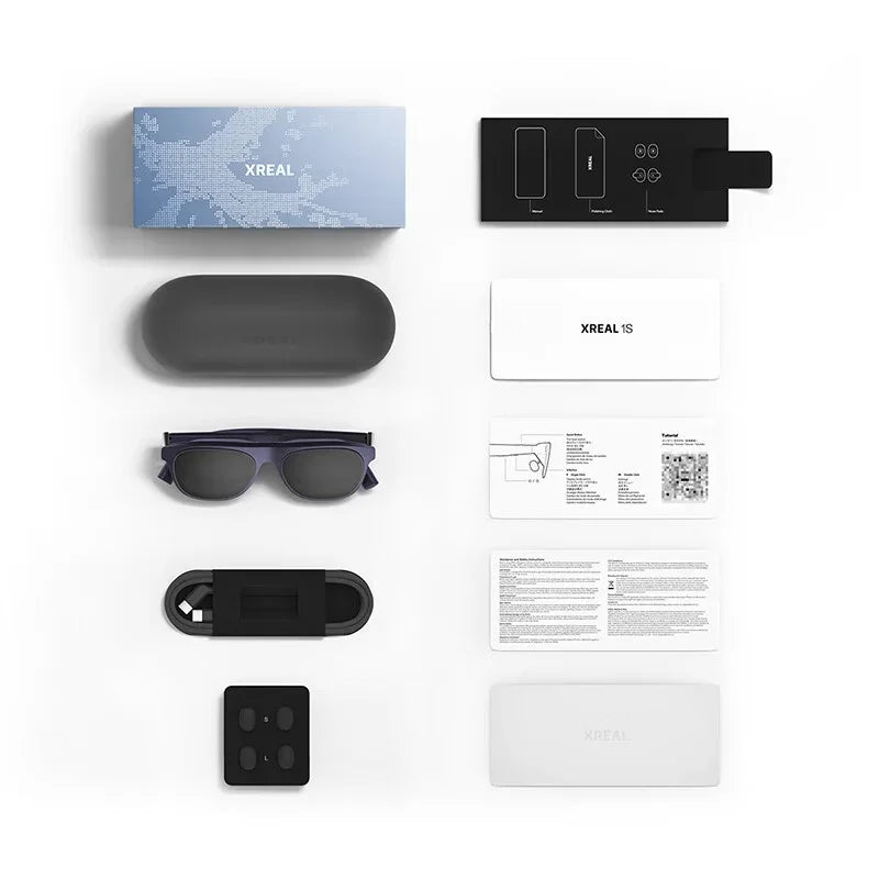 De XREAL 1S AR-bril in donkerpaars, met zwart kunststof kastje en witte verpakking, geschikt voor mobiele virtuele realiteit en gaming. Compacte, draa