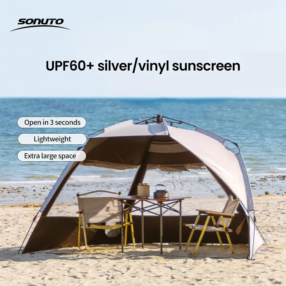Zilveren vinyl zonnescherm met UPF60+ bescherming, geplaatst op het strand met twee vouwstoelen en tafel. Ideaal voor zonbescherming tijdens kamperen 
