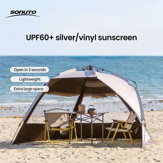 Zilveren vinyl zonnescherm met UPF60+ bescherming, geplaatst op het strand met twee vouwstoelen en tafel. Ideaal voor zonbescherming tijdens kamperen 