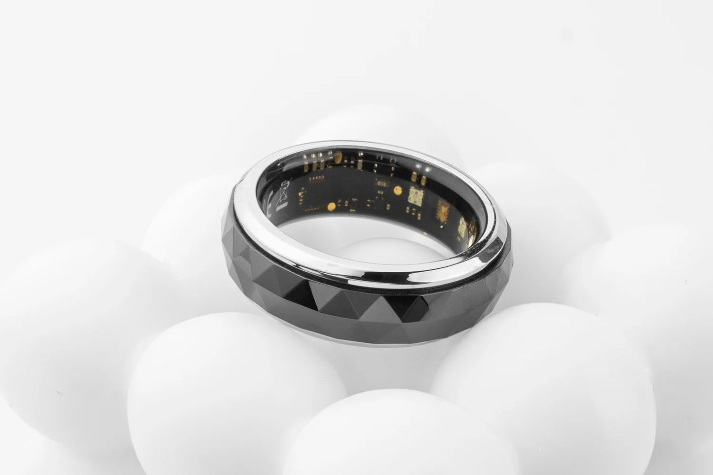 Een COLMi slimme ring met glanzend zilveren rand en facettenstructuur, voorzien van een actieve sensor en groene LED-indicator, geschikt voor dagelijks gebruik en technologische toepassingen. - Foto 29