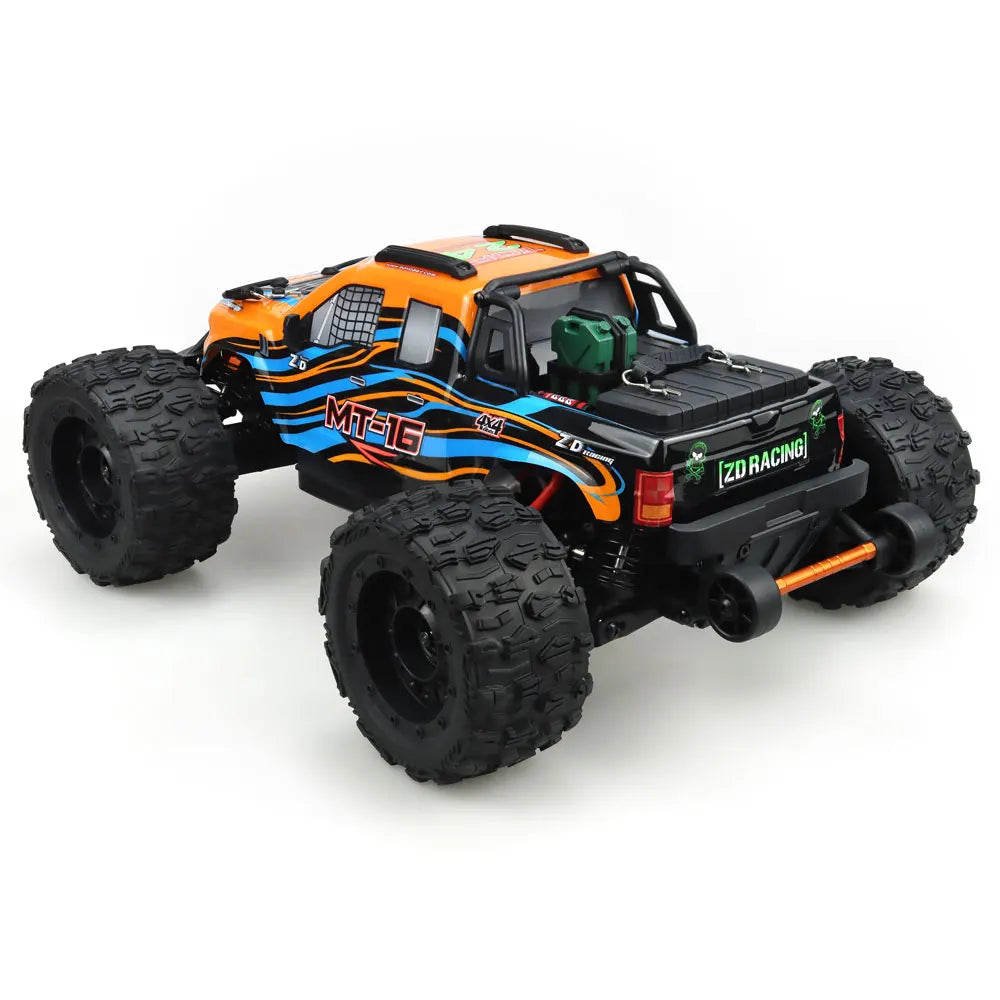 Oranje en blauwe RC monstertruck met grote zwarte banden en zichtbare 'MT-16' sticker, geplaatst naast zijn zwarte stuurunit voor speelplezier op zand