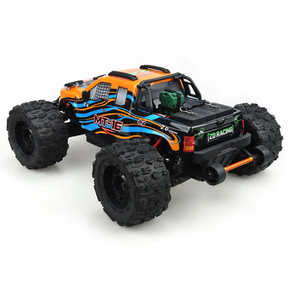 Oranje en blauwe RC monstertruck met grote zwarte banden en zichtbare 'MT-16' sticker, geplaatst naast zijn zwarte stuurunit voor speelplezier op zand