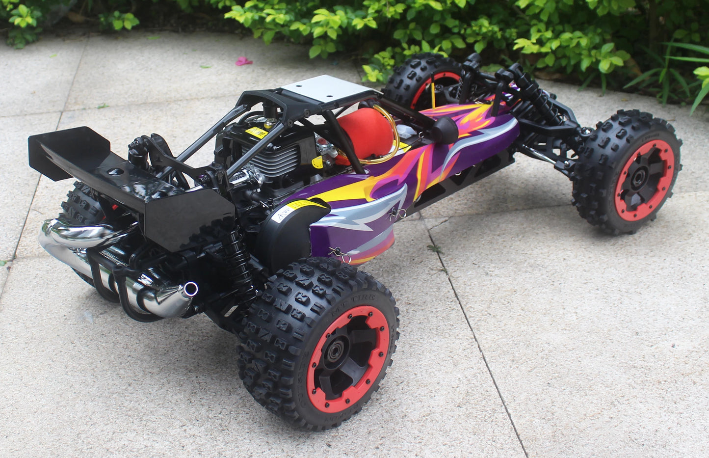 Groene camouflage RC buggy met zwarte rubberen banden en zichtbare schokdempers, klaar voor terreinrijden. Perfect voor outdoor speelplekken en avontu