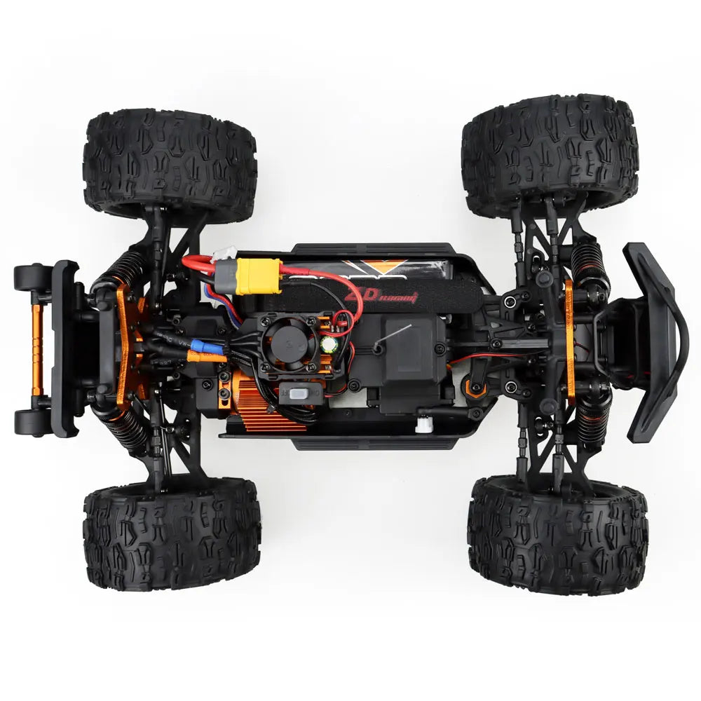 Oranje en blauwe RC monstertruck met grote zwarte banden en zichtbare "MT-16" sticker, geplaatst naast zijn zwarte stuurunit voor speelplezier op zach