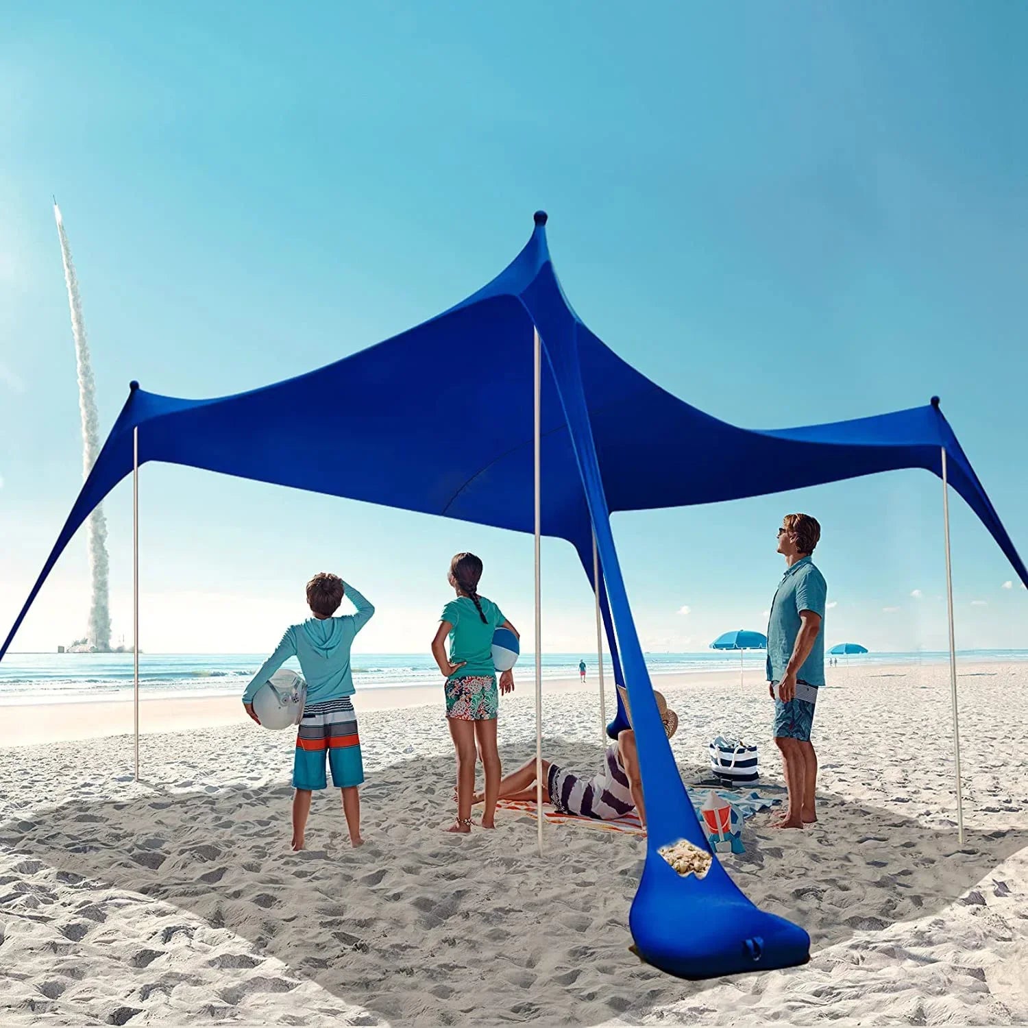 Blauwe zonnescherm tent met metalen staven biedt schaduw op het strand. Een vrouw in bikini en strohoed rust op een ligstoel onder de tent, perfect vo