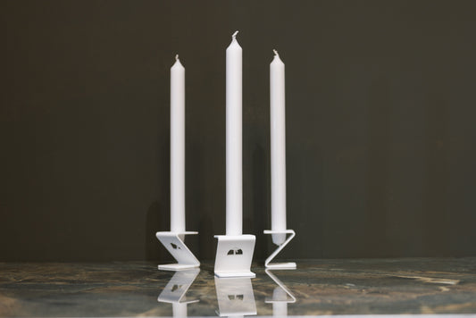 Drie witte kaarsen in minimalistische, witte houder op glanzende marmeren tafel. Perfect voor een moderne, elegante sfeer in woon- of feestruimte.