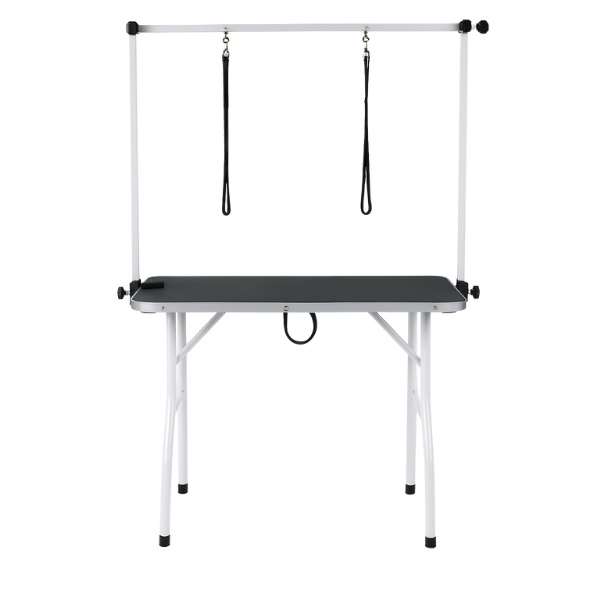 Een witte, vouwbare hondensnijtafel met zwarte oppervlakte en twee hangende riemen, geschikt voor professionele hondensnijden en -kapperij.