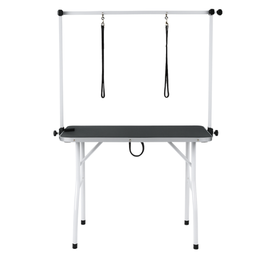 Een witte, vouwbare hondensnijtafel met zwarte oppervlakte en twee hangende riemen, geschikt voor professionele hondensnijden en -kapperij.