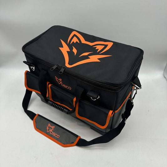 Zwarte OSO toolbag met oranje logo en verstelbare schouderband, geplaatst op een bouwplaats. Geschikt voor bouwvakkers en handwerkers die op zoek zijn naar een robuuste, draagbare opslagoplossing.